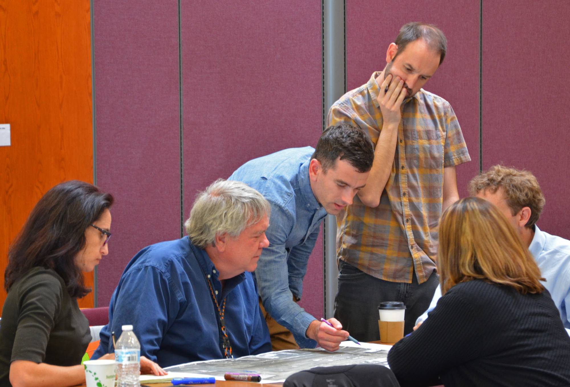 A photo of multiple employees standing together reviewing a document