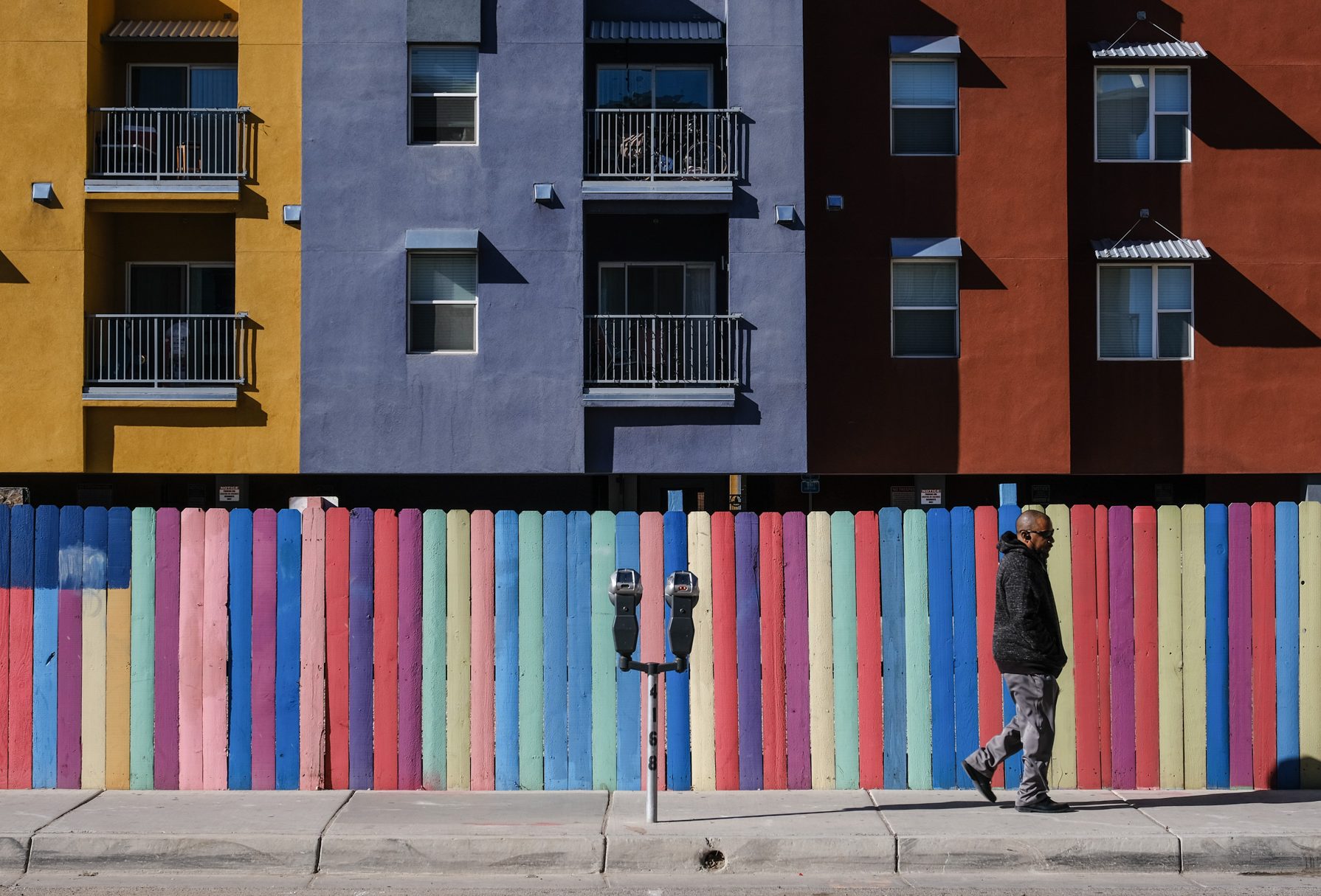 A picture of a man walking in front of a colorful wall