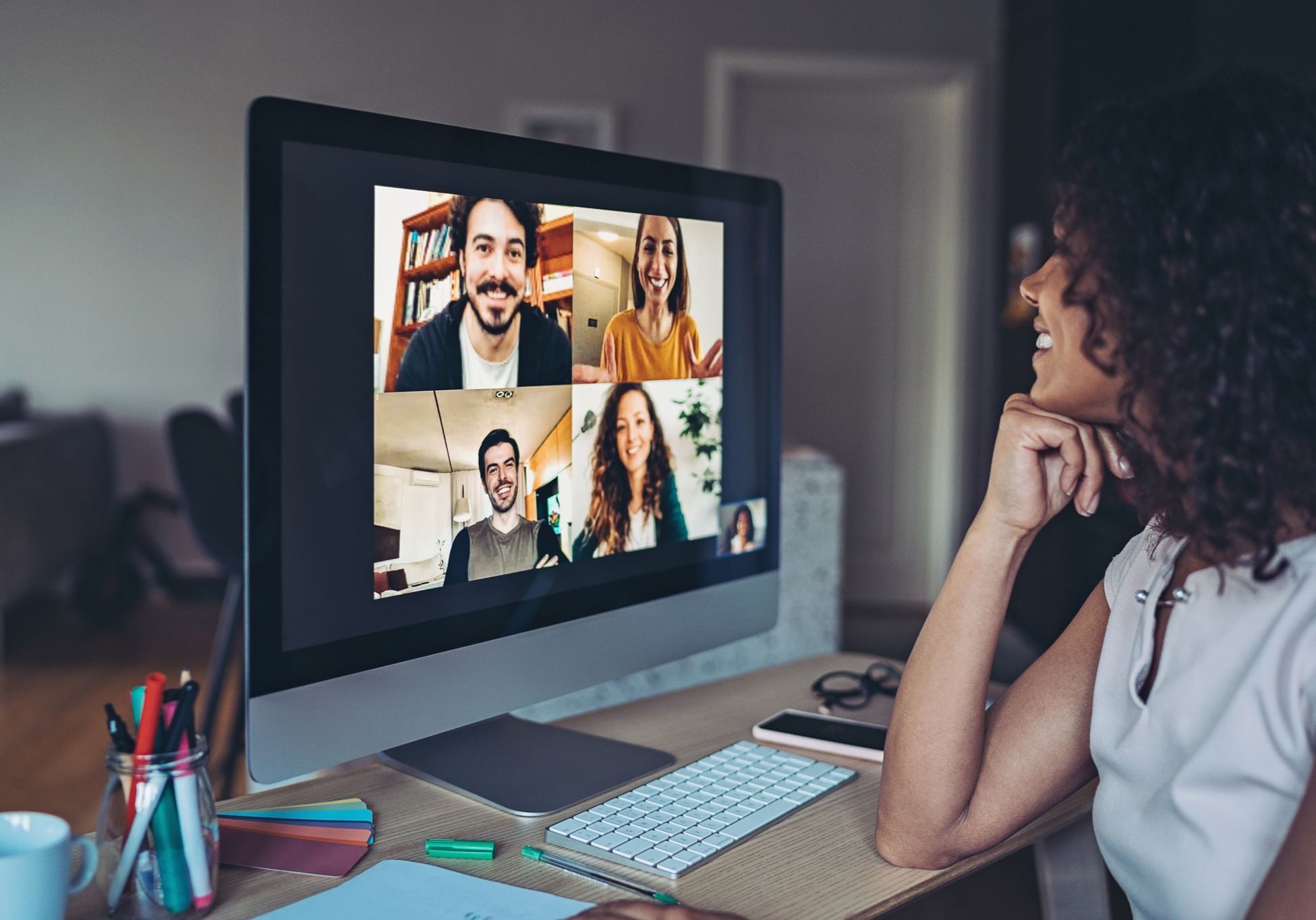 a woman sitting at her desk in front of a computer participating in a video conference call